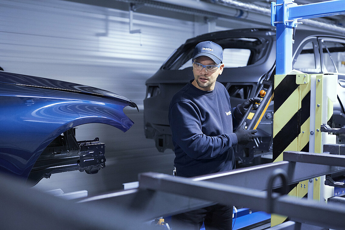 A Leadec employee troubleshooting the conveyor system in an automotive factory.
