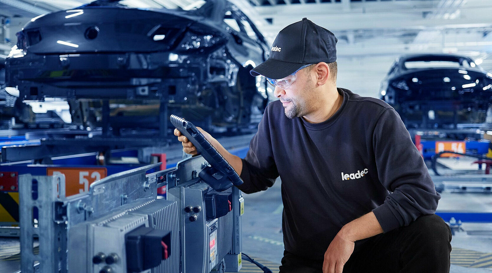 A Leadec employee configures an inverter at a conveyor belt.