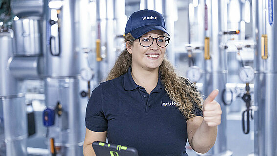 Female Leadec in a technical room employee hold thumbs up.